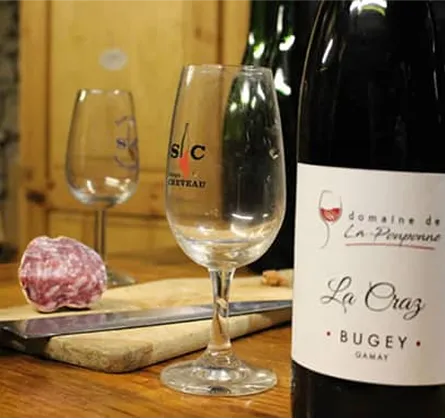 Photo d'un bouteille de vin avec un morceau de saucisson sur une place et un verre